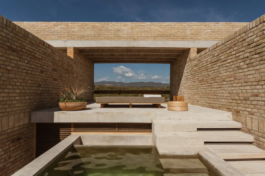 Terraço com piscina privativa e tijolos aparentes no Hotel Terrestre, mesclando concreto e arquitetura vernacular.