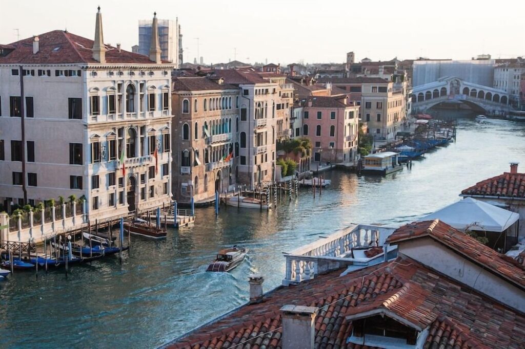 Fachada do Palazzo Papadopoli no Grand Canal com a Ponte de Rialto ao fundo no Aman Venice, ícone dos hotéis de Veneza.