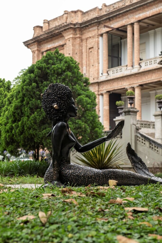 Escultura no Jardim da Pinacoteca Luz com fachada histórica em passeios de arquitetura em são paulo.