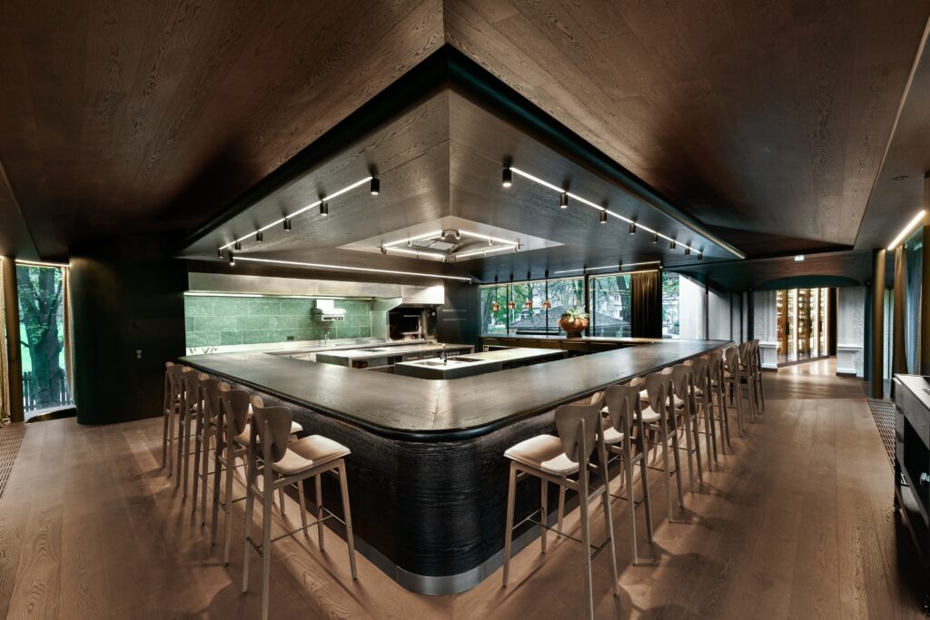 Balcão e cozinha aberta com mármore verde e vista para o parque no restaurante Atelier Moessmer Norbert Niederkofler.