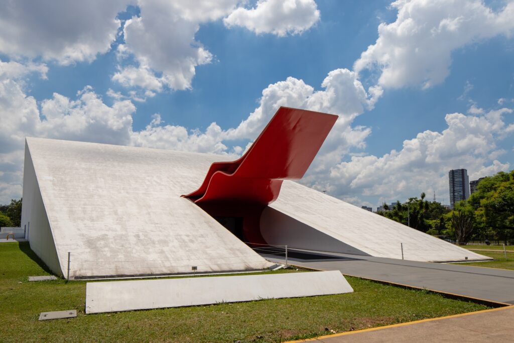 Auditório Ibirapuera com escultura vermelha e concreto monumental, ícone modernista e do brutalismo em São Paulo.