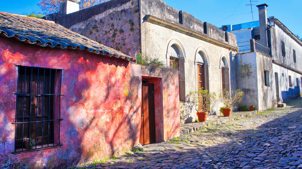 Rua histórica de pedra com casas coloniais e fachadas rústicas em Colonia del Sacramento, parada clássica em um roteiro no Uruguai.