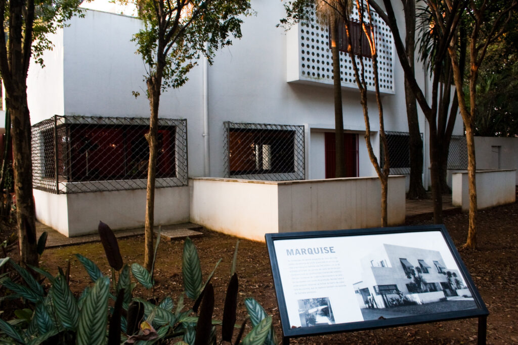 Fachada da Casa Modernista e jardins tropicais, marco que antecede o Brutalismo em São Paulo.