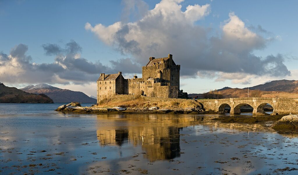 Castelo de Eilean Donan e ponte de pedra em ilhota lacustre, ícone da arquitetura escocesa nas Highlands.