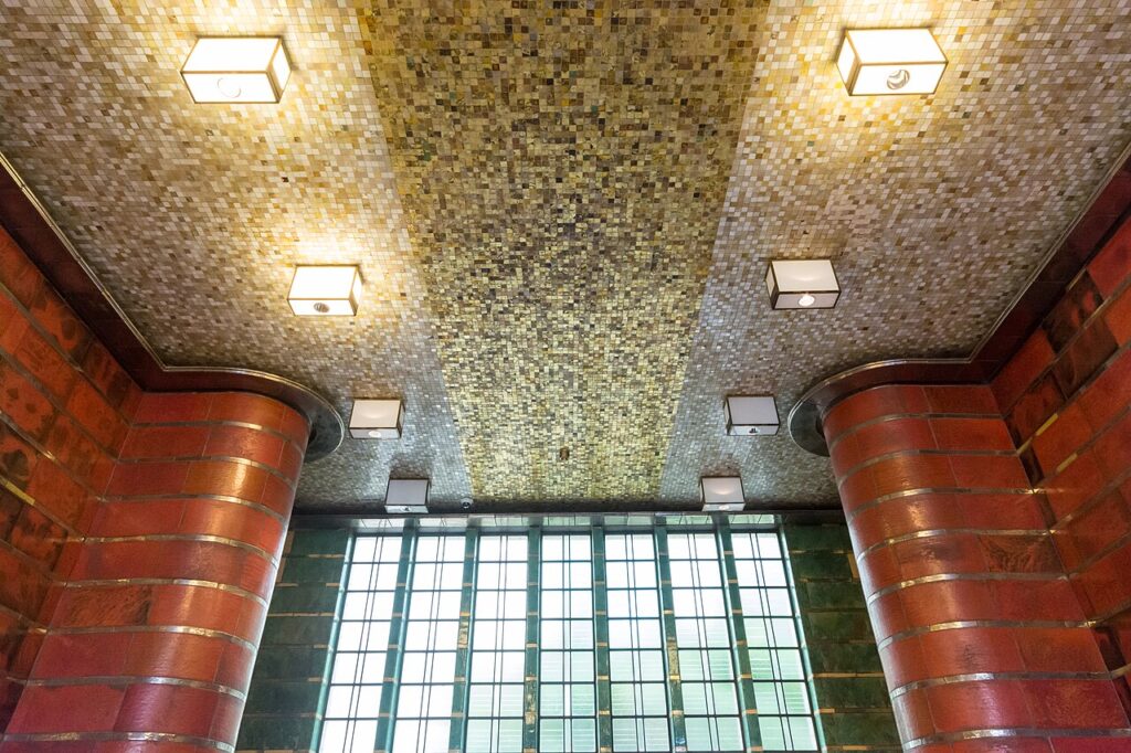 Teto em mosaico dourado e plafons geométricos evidenciam a iluminação no Art Déco no edifício Brahmskontor em Hamburgo.