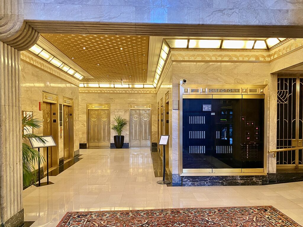 Lobby com mármore claro, teto dourado e detalhes em bronze no Carbide and Carbon Building, exemplar de art deco.