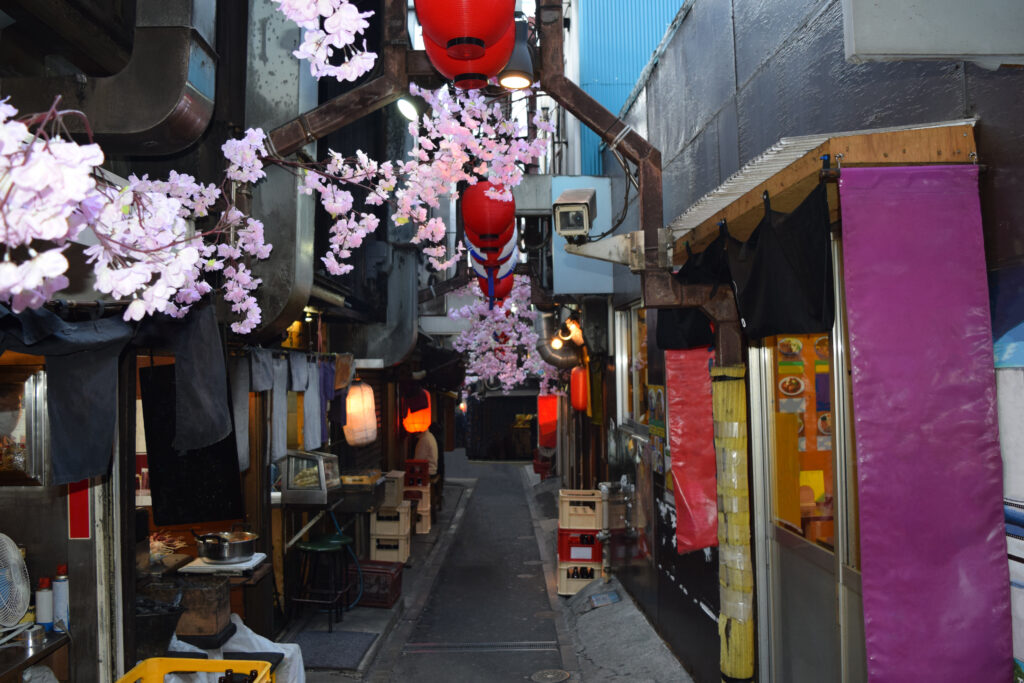 Beco de Omoide Yokocho em Shinjuku com izakayas e lanternas vermelhas, vizinhança tradicional impactada pela expansão do Airbnb.