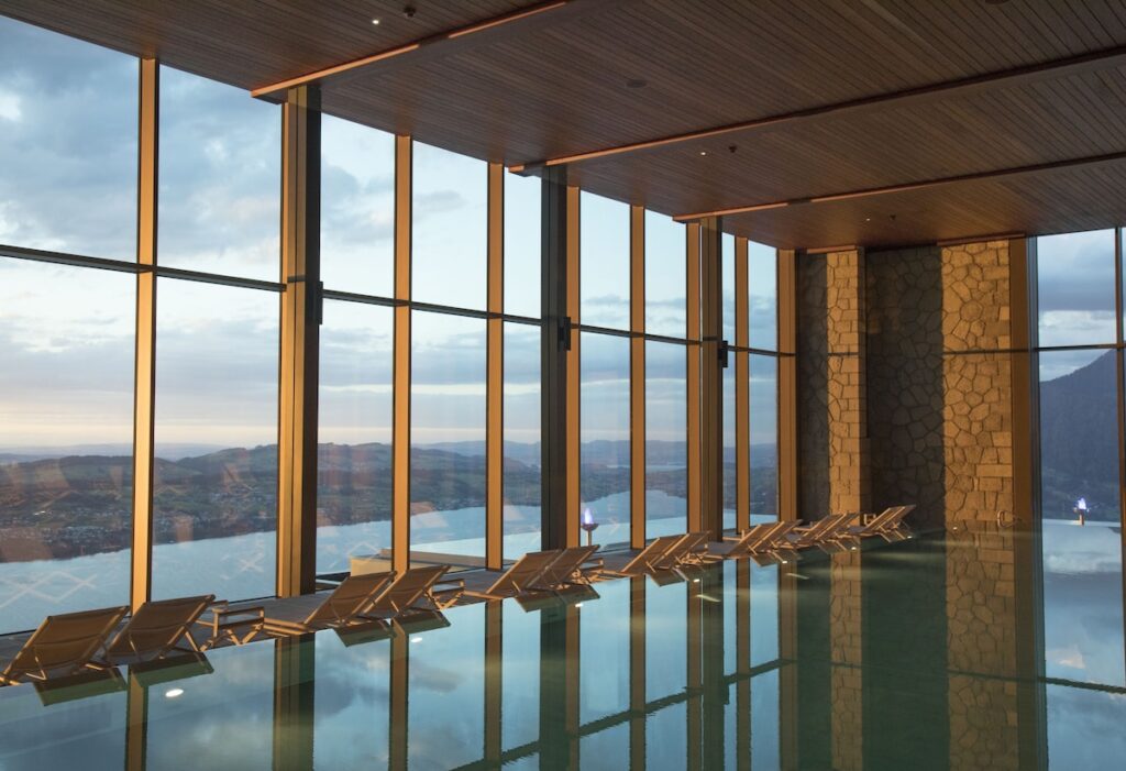 Piscina interna do Alpine Spa no Bürgenstock Hotel com vista para o lago, ápice do bem-estar em hotéis de luxo nos Alpes suíços.