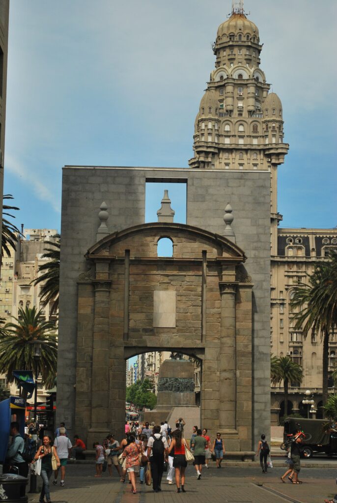 Pórtico da Puerta de la Ciudadela emoldurando o imponente Palácio Salvo em Montevidéu, marco essencial de um roteiro no Uruguai.