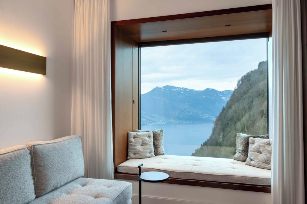 Quarto com bay window em nogueira e vista panorâmica no Bürgenstock Hotel, referência em hotéis de luxo nos Alpes suíços.