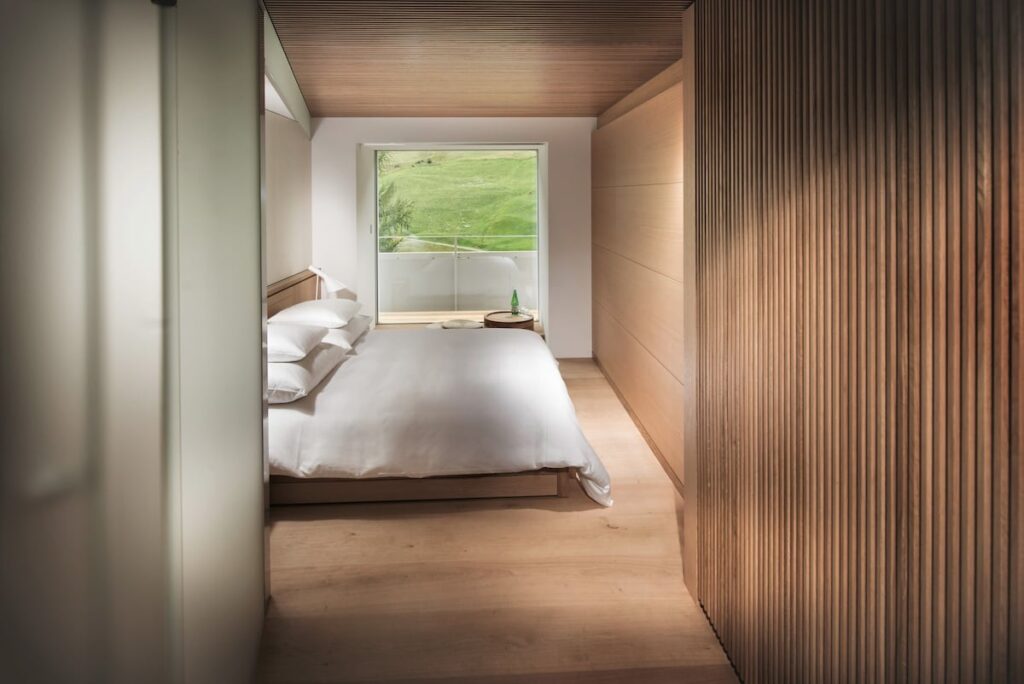 Quarto minimalista em madeira criado por Tadao Ando no House of Architects, destaque em hotéis de luxo nos Alpes suíços.