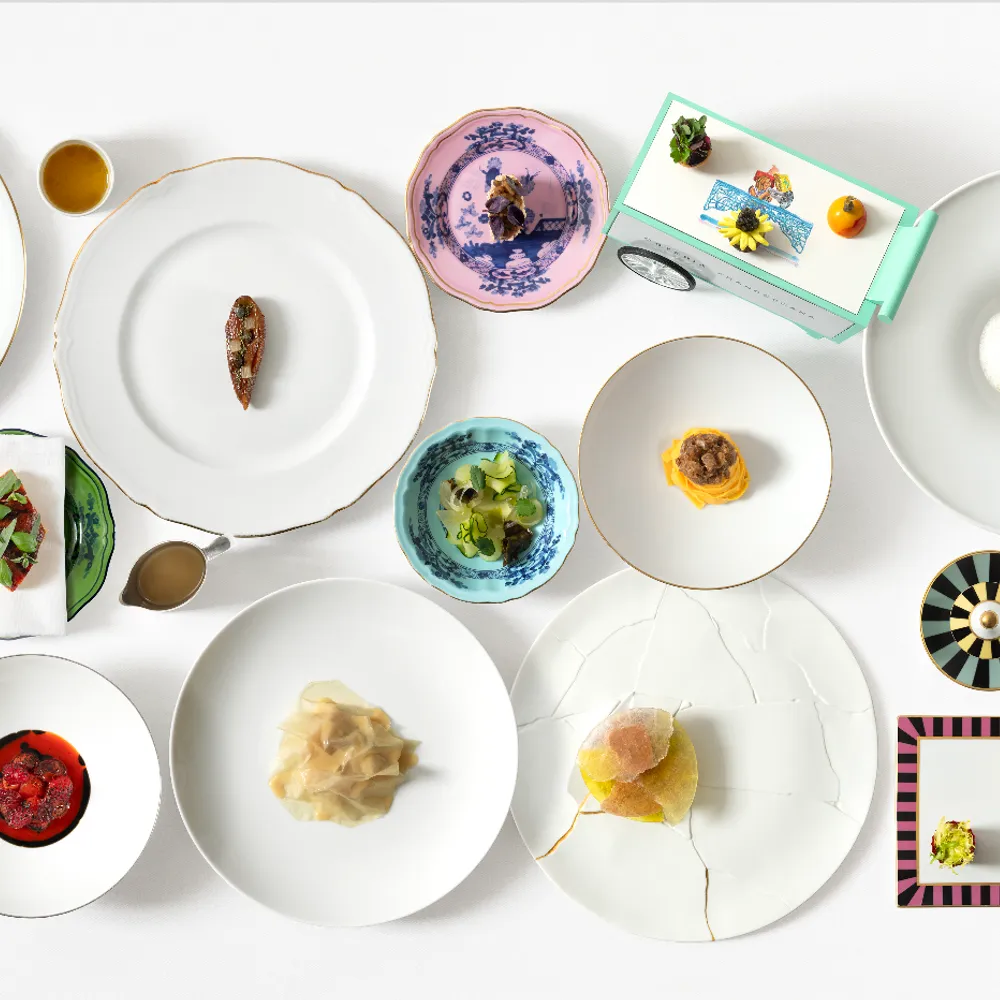 Composição de pratos autorais e porcelanas clássicas na Osteria Francescana, destacando o design de mesa e a alta gastronomia em Modena.