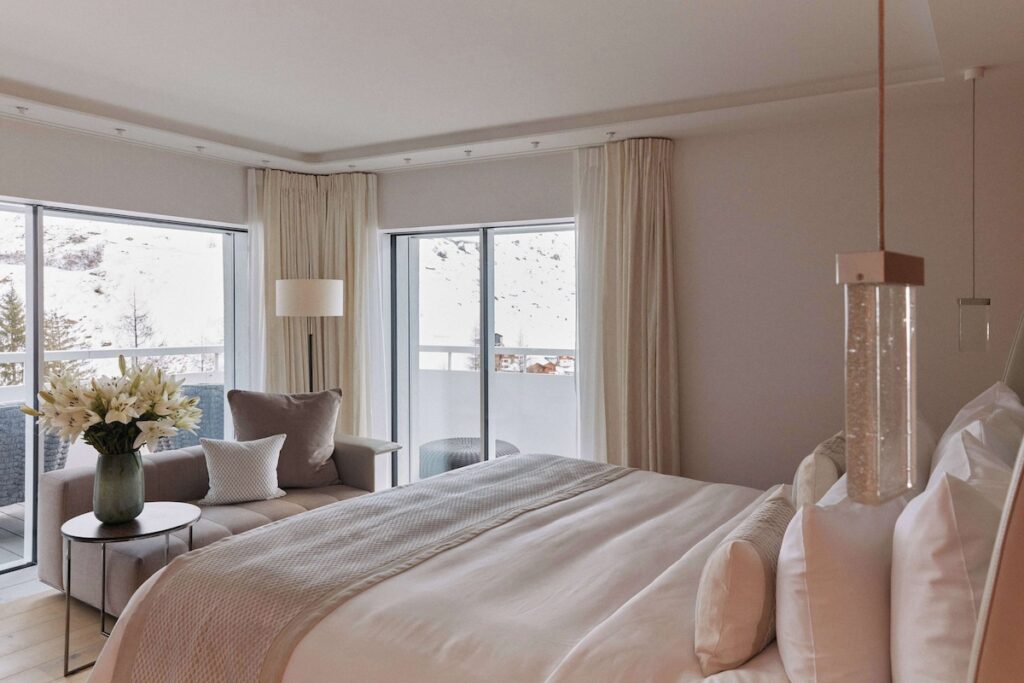 Suíte do 7132 Hotel com vista panorâmica para a neve, exemplo de refúgio e sofisticação em hotéis de luxo nos Alpes suíços.