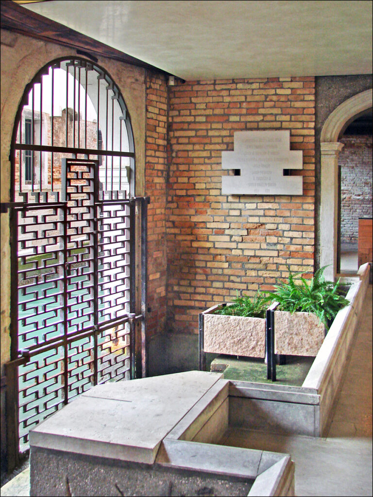 Hall da maré alta projetado por carlo scarpa com comportas em ferro vazado, patamares em pedra da Ístria e alvenaria de tijolos aparentes.
