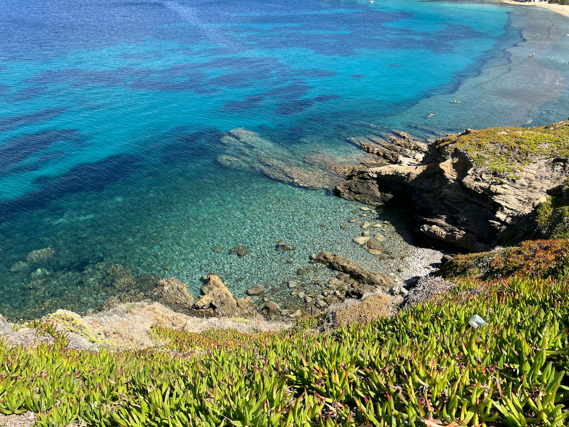 Dica de viagem em Mykonos: praia com águas cristalinas e rochas, vista de cima