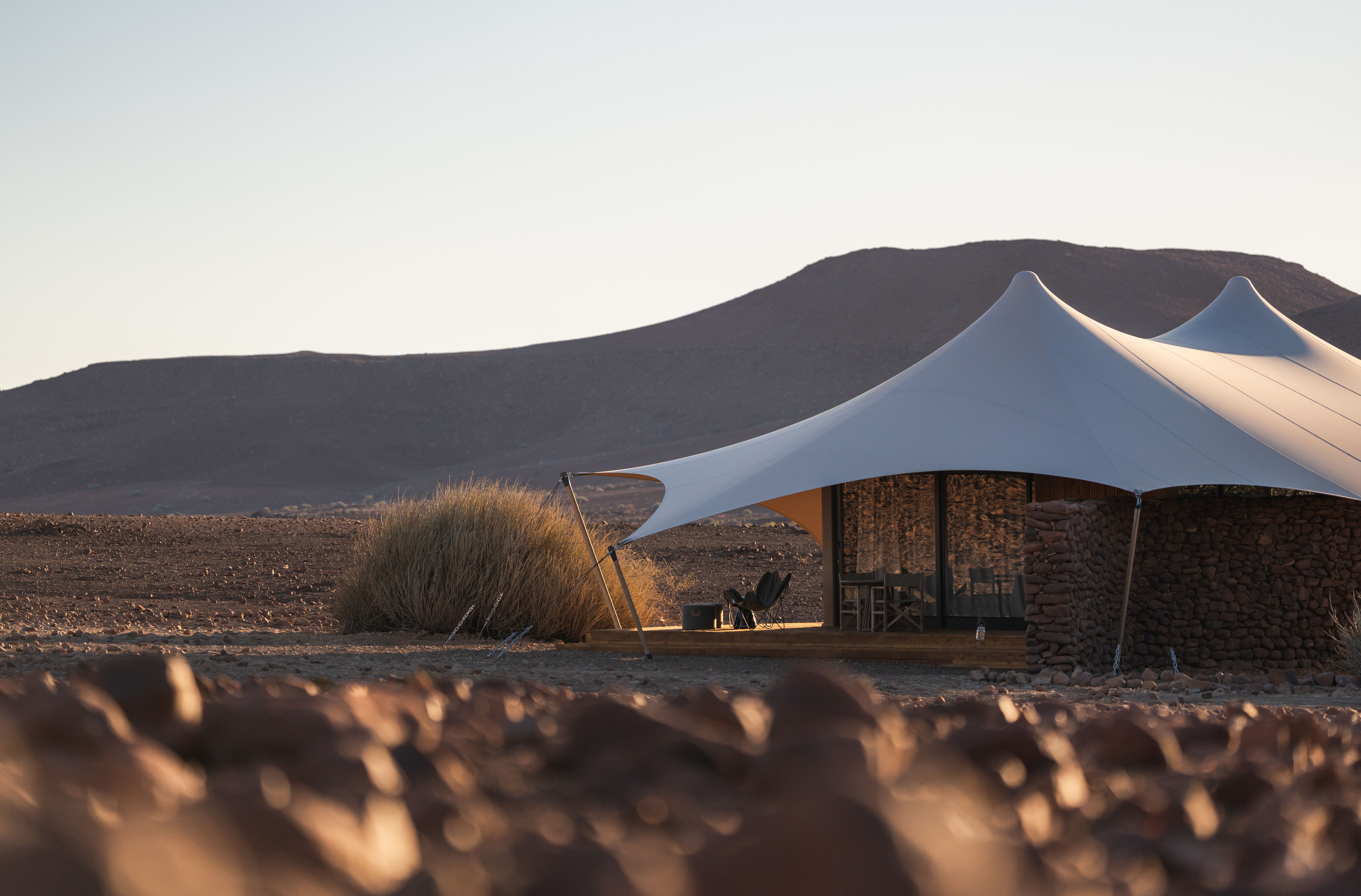 Tenda tensionada integrada à paisagem montanhosa do Desert Rhino Camp.