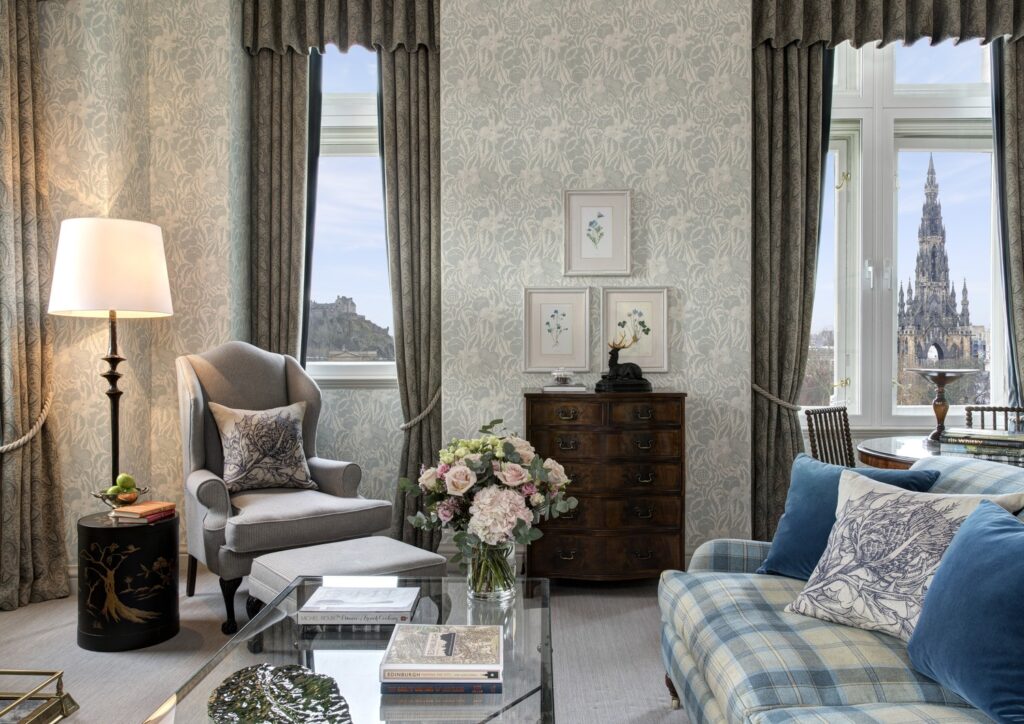 Sala de estar da Castle View Suite no Balmoral hotel com estofados em tartan escocês, papel de parede botânico e vista para o Castelo de Edimburgo.