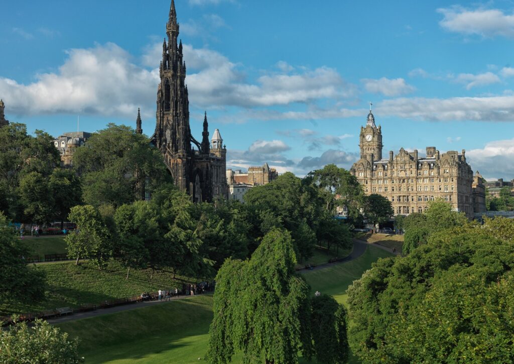 Vista panorâmica do Balmoral hotel e sua torre do relógio a partir dos jardins de Princes Street Gardens com o Scott Monument em Edimburgo.