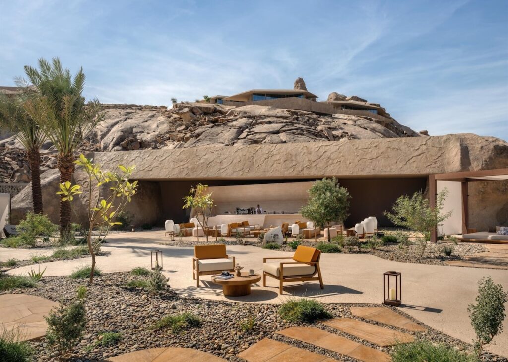 Área externa de estar com bar integrado à base rochosa no Desert Rock Hotel.