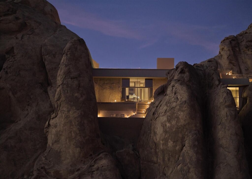 Iluminação noturna e arquitetura integrada às fendas rochosas no Desert Rock Hotel.