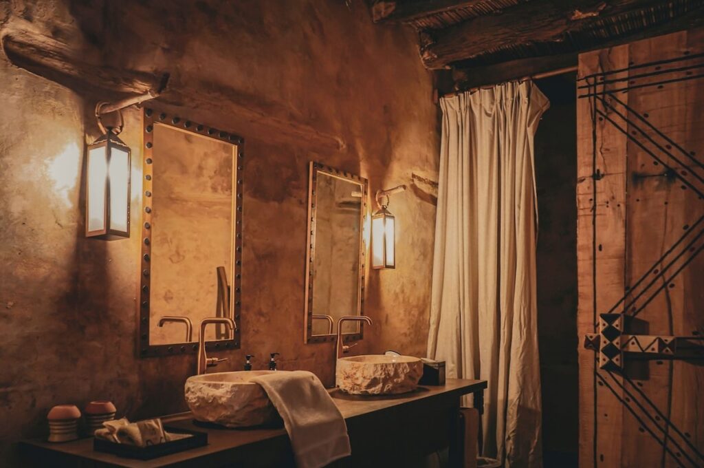 Banheiro com cubas duplas de pedra e iluminação acolhedora em hotel no deserto de AlUla.