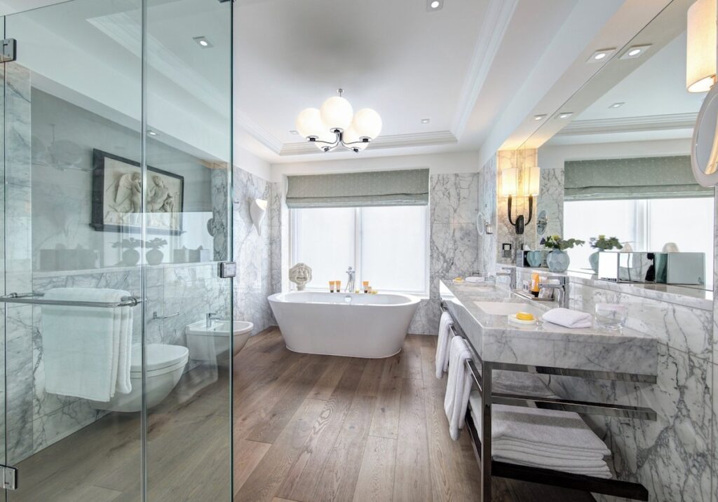 Banheiro luxuoso de suíte no Balmoral hotel com banheira de imersão, bancada dupla em mármore Carrara e piso aquecido em madeira.