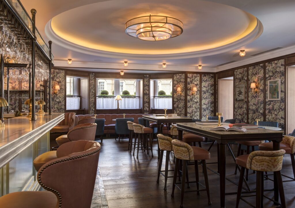Bar da Brasserie Prince no Balmoral hotel com papel de parede botânico, boiserie de madeira escura, teto circular iluminado e banquetas de couro.
