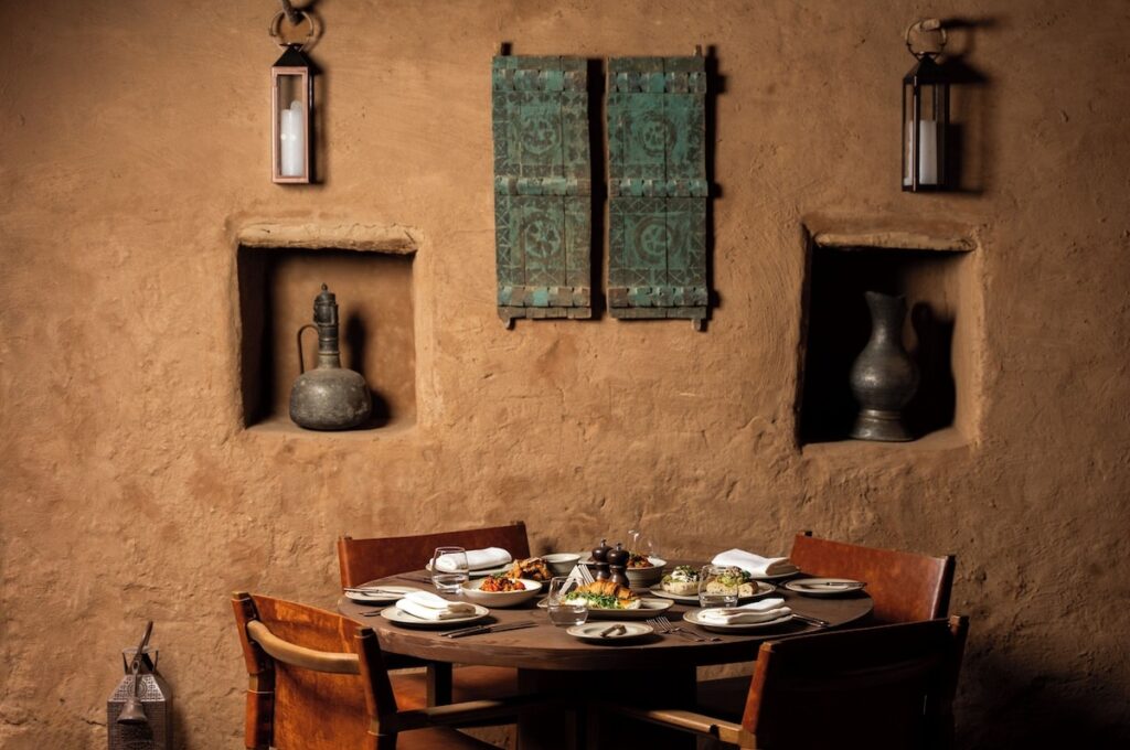 Mesa posta de jantar em ambiente de adobe com ânforas históricas no Dar Tantora.