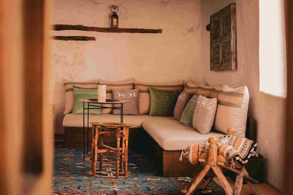 Sala de estar intimista com sofá modular e tapeçaria típica em hotel no deserto de AlUla.