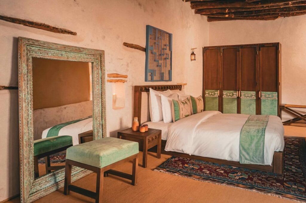 Suíte ampla com espelho de piso e armário de marcenaria autoral em hotel no deserto de AlUla.