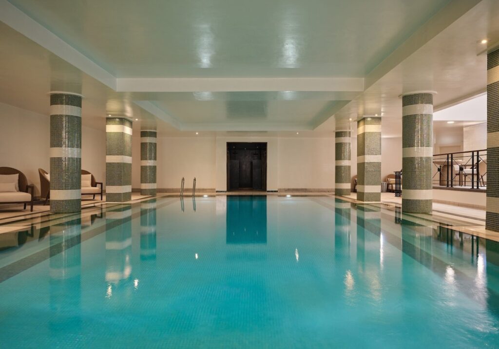 Piscina coberta aquecida do spa no Balmoral hotel com colunas cilíndricas revestidas em pastilhas listradas e iluminação relaxante.