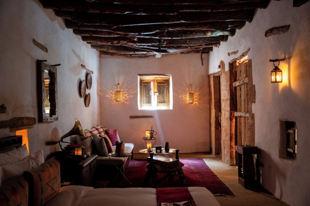 Quarto com teto de toras de madeira e arandelas de fibra em hotel no deserto de AlUla.