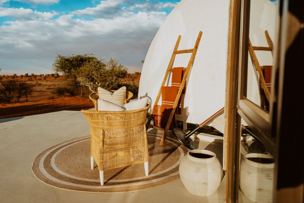Área de estar externa com poltronas de fibra natural e peças de cerâmica em sofisticado retiro no deserto.
