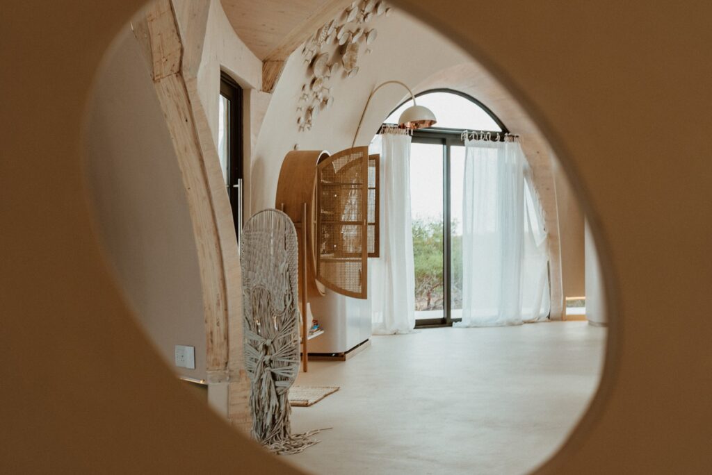 Enquadramento circular revelando arcos de madeira e peças têxteis artesanais nos interiores do Reverie Kalahari Pod.