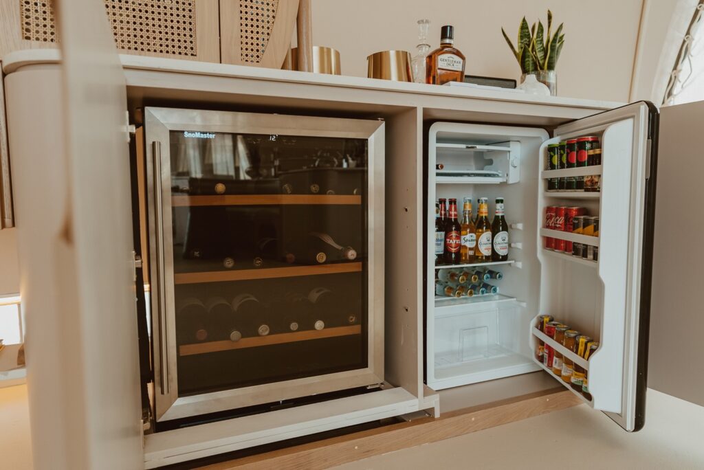 Adega climatizada e frigobar premium embutidos em marcenaria sob medida em refinado retiro no deserto.