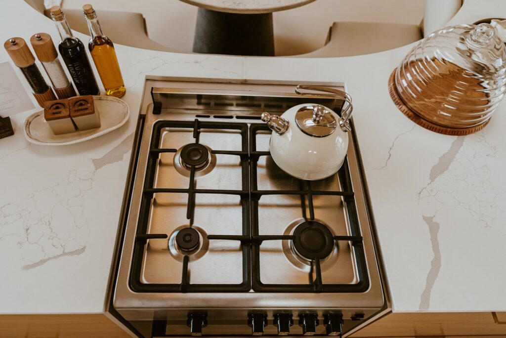 Cooktop embutido em bancada de quartzo calacata e temperos gourmet em cozinha intimista de retiro no deserto.