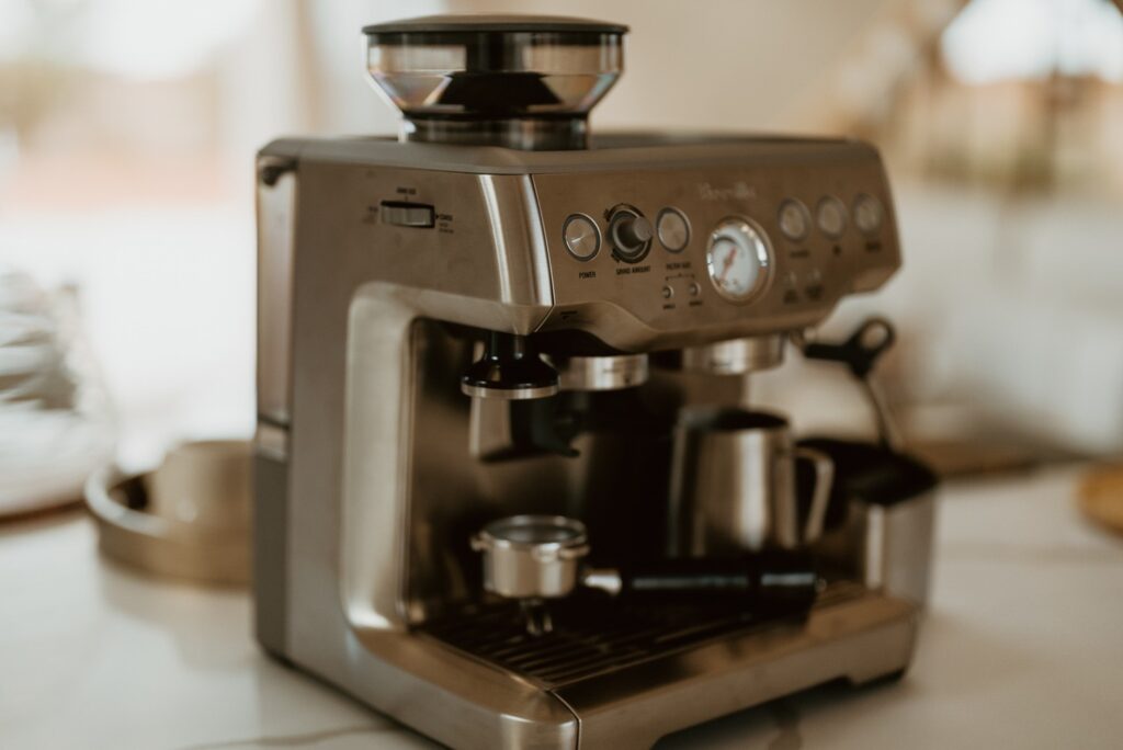 Máquina de café espresso profissional em aço inox sobre bancada de quartzo na cozinha de retiro no deserto.