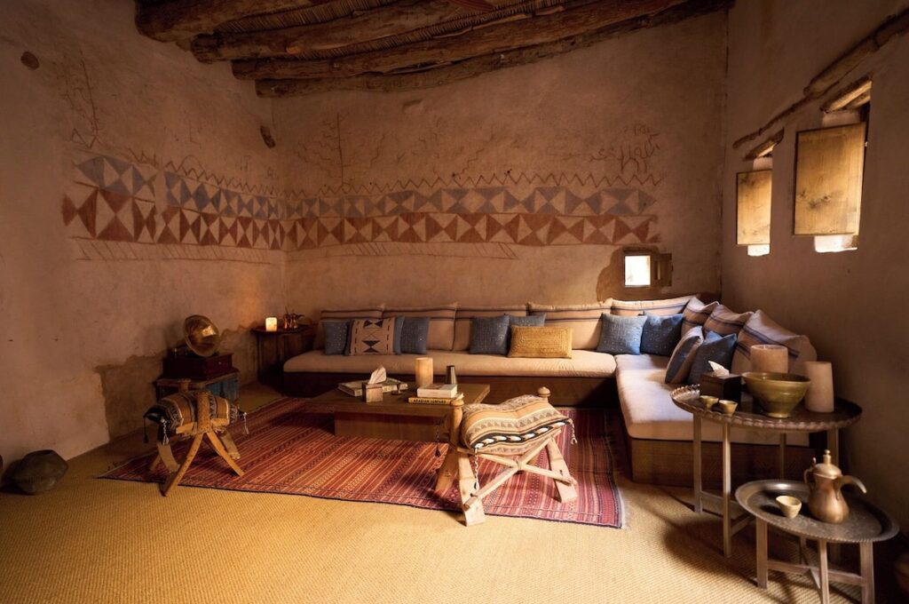 Sala de estar em estilo majlis com pinturas murais geométricas em hotel no deserto de AlUla.