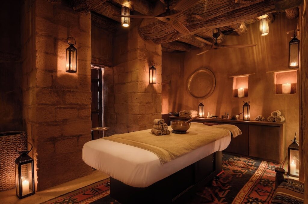 Sala de massagem do spa com paredes de adobe e iluminação à luz de velas no Dar Tantora.