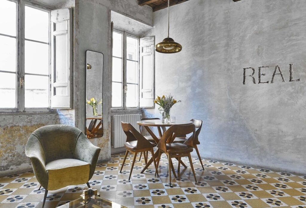 Sala de jantar na Suíte Pasquino do G-Rough Roma com piso hidráulico original e mesa de design italiano.