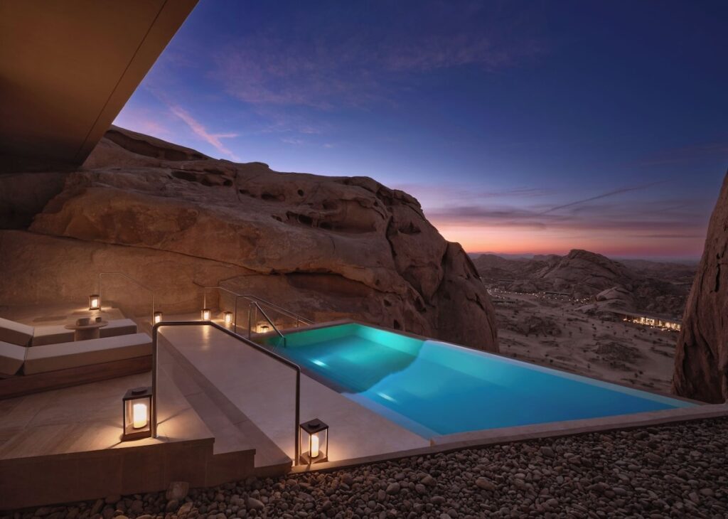 Piscina de borda infinita entre rochas ao crepúsculo no Desert Rock Hotel.