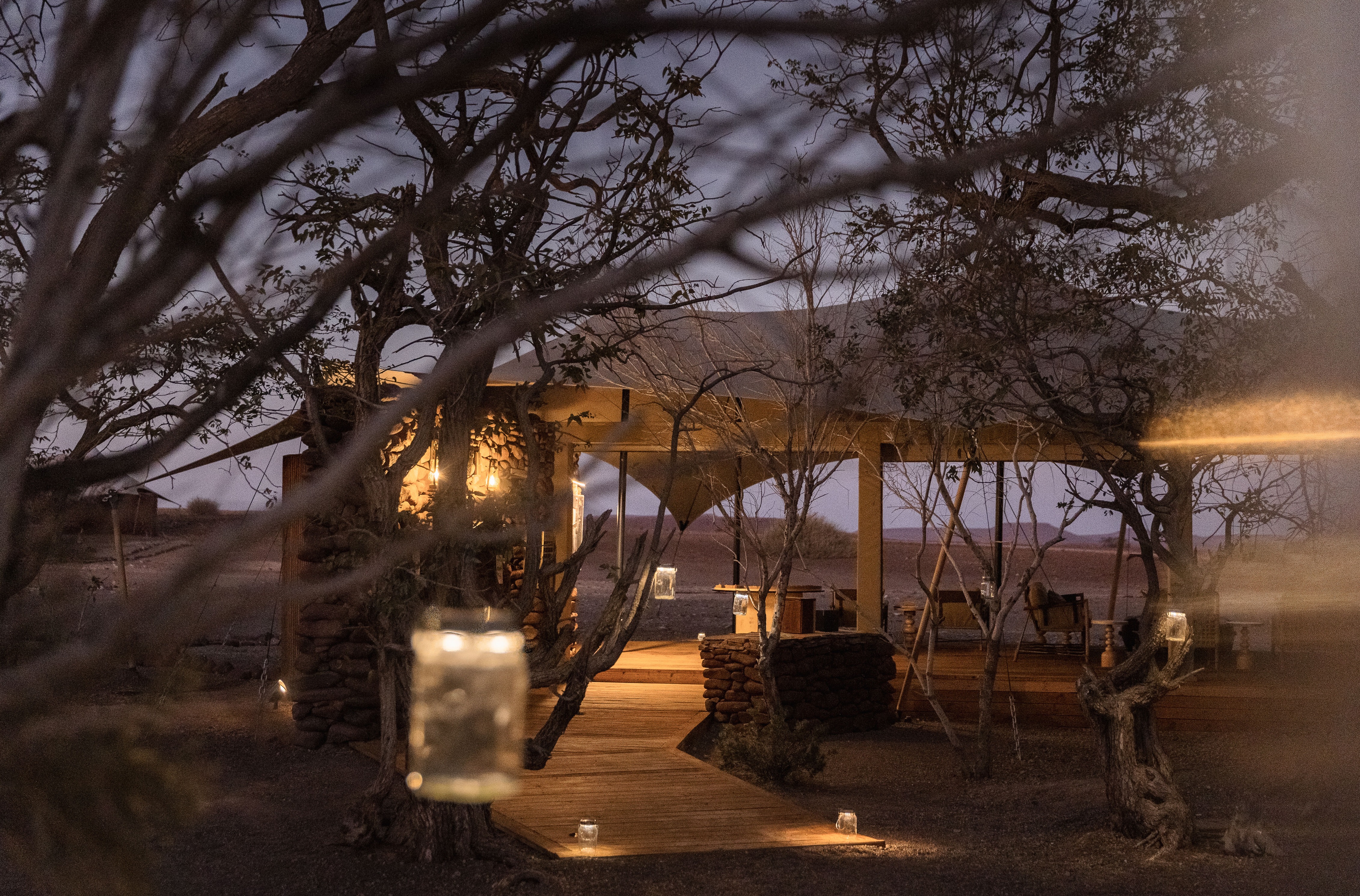 Passarela com lanternas cênicas suspensas nas árvores no Desert Rhino Camp.