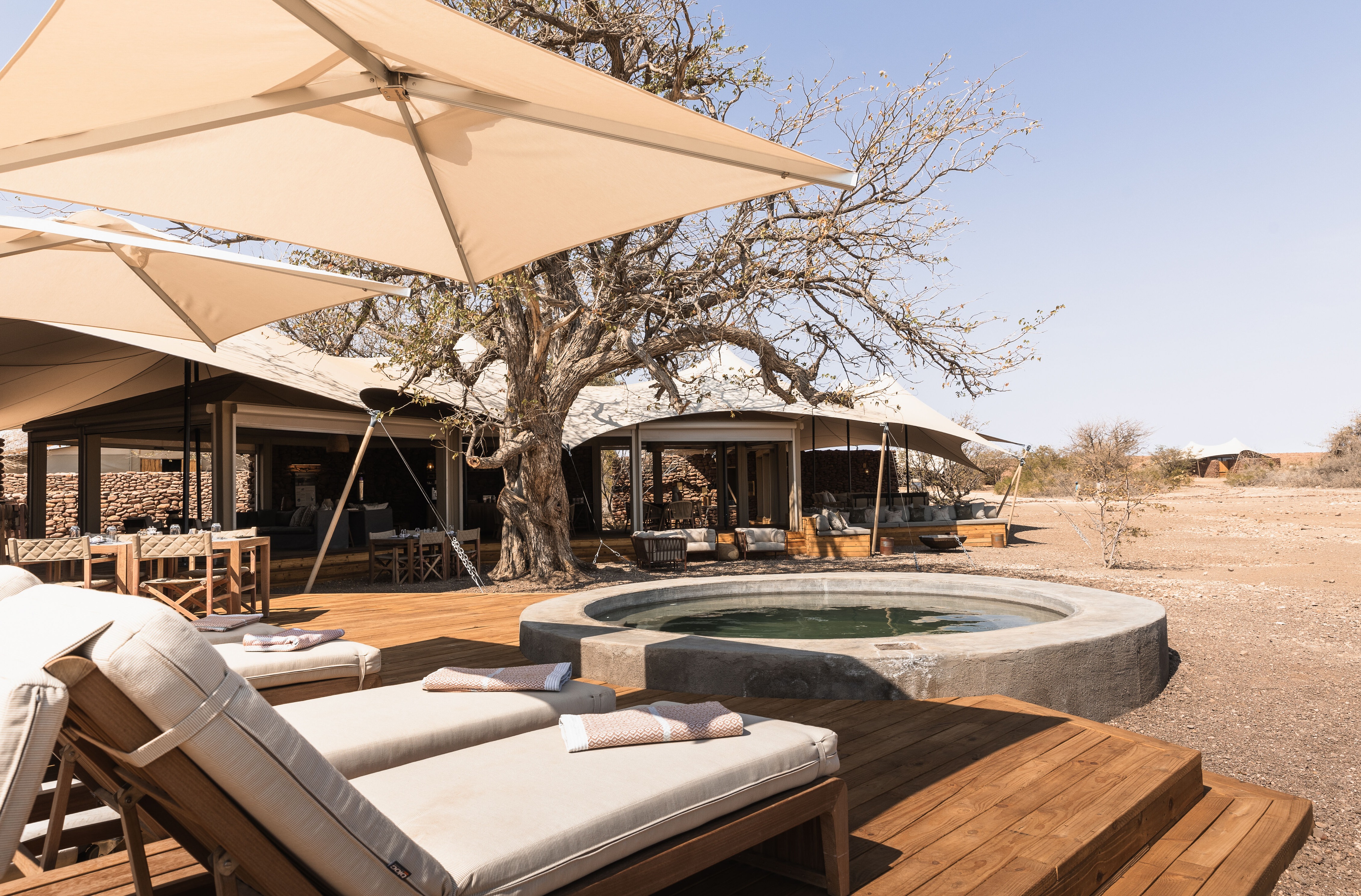 Área de solário com piscina e vista para a imensidão no Desert Rhino Camp.