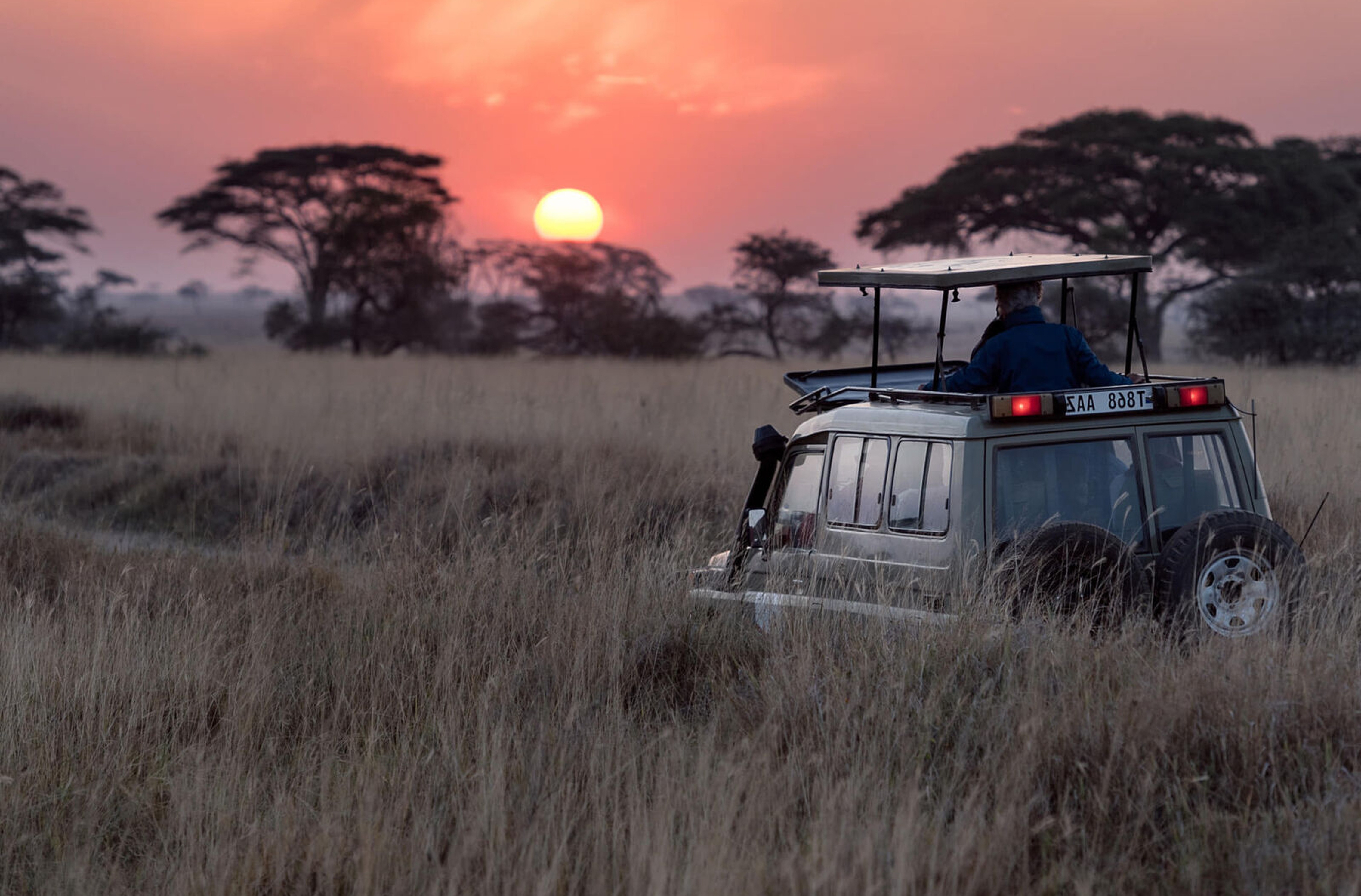 Veículo 4x4 de safári ao pôr do sol na savana perto do Desert Rhino Camp.