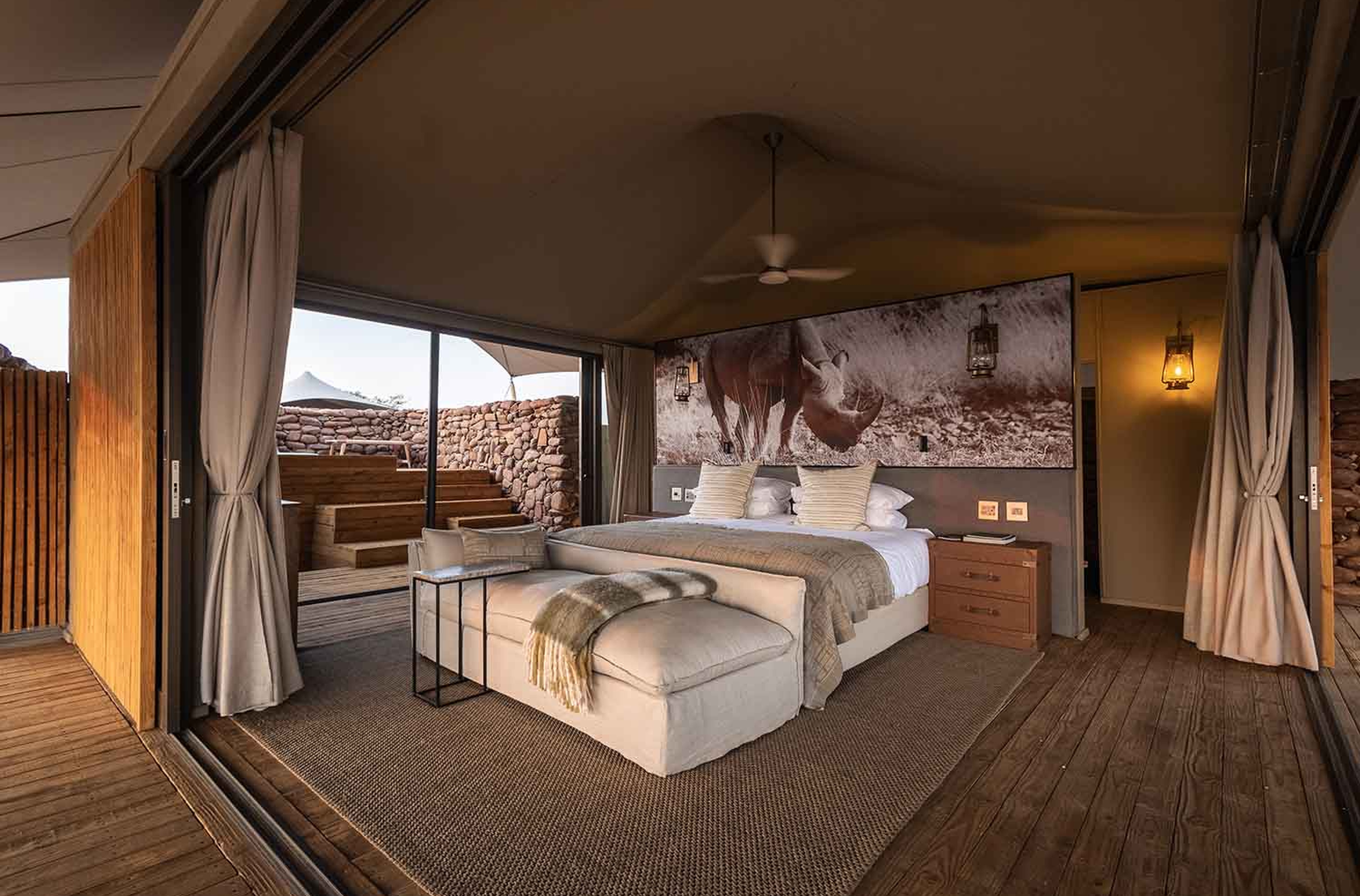 Suíte de luxo tendada com cama king e vista panorâmica no Desert Rhino Camp.