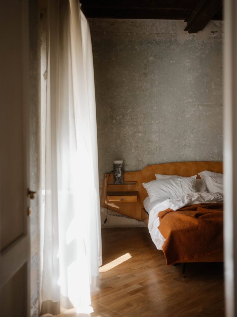 Quarto com cabeceira mostarda curva e luz natural no hotel boutique G-Rough Roma.
