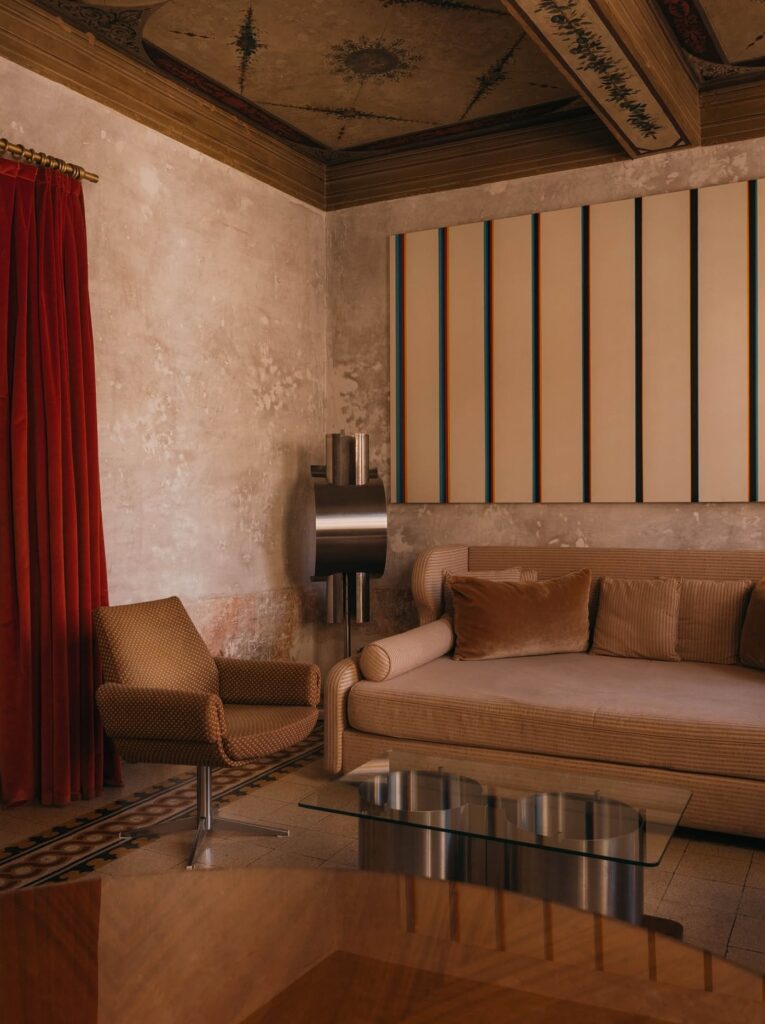 Living com poltrona giratória vintage e luminária de aço escultórica no hotel G-Rough Roma.