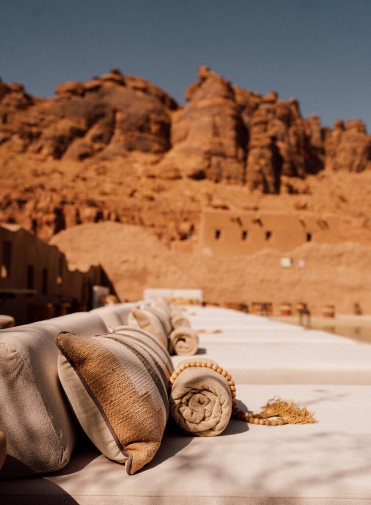 Detalhes têxteis artesanais em daybeds junto à paisagem árida em hotel no deserto de AlUla.