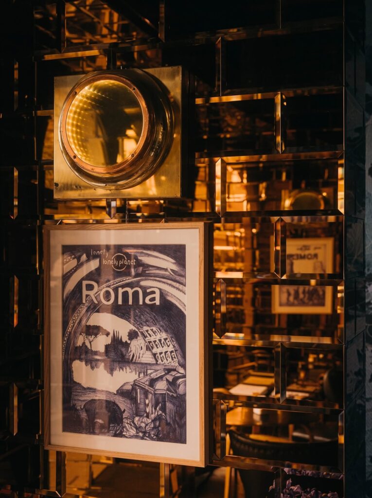 Quadro com gravura de Roma em divisória espelhada no Gallery Bar do hotel G-Rough Roma.
