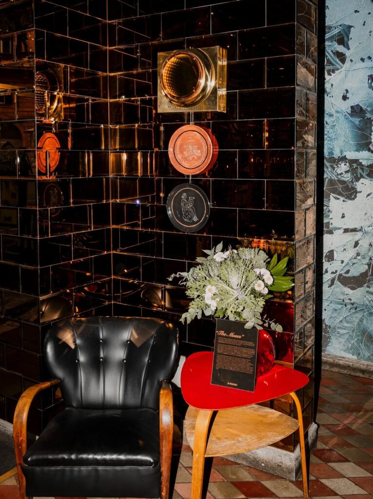 Poltrona retrô preta e mesa de apoio vermelha no Gallery Bar do hotel boutique G-Rough Roma.